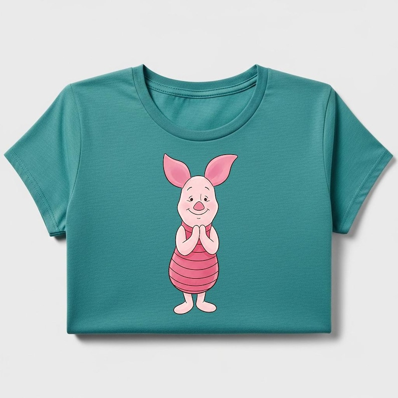 May include: Teal-colored t-shirt featuring a cartoon illustration of Piglet from Winnie the Pooh. Piglet is depicted with pink ears, a pink and red striped torso, and a smiling expression. The shirt has a crew neck and short sleeves.