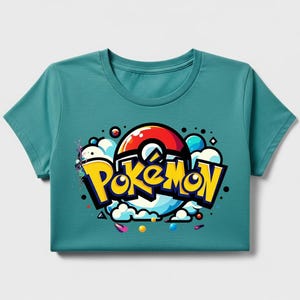 Peut inclure: T-shirt turquoise avec le mot "Pok&eacute;mon" en jaune, soulign&eacute; de noir, et un design de Pok&eacute; Ball rouge et blanc. Le graphisme comprend des nuages blancs, des accents bleus et jaunes et des points color&eacute;s.