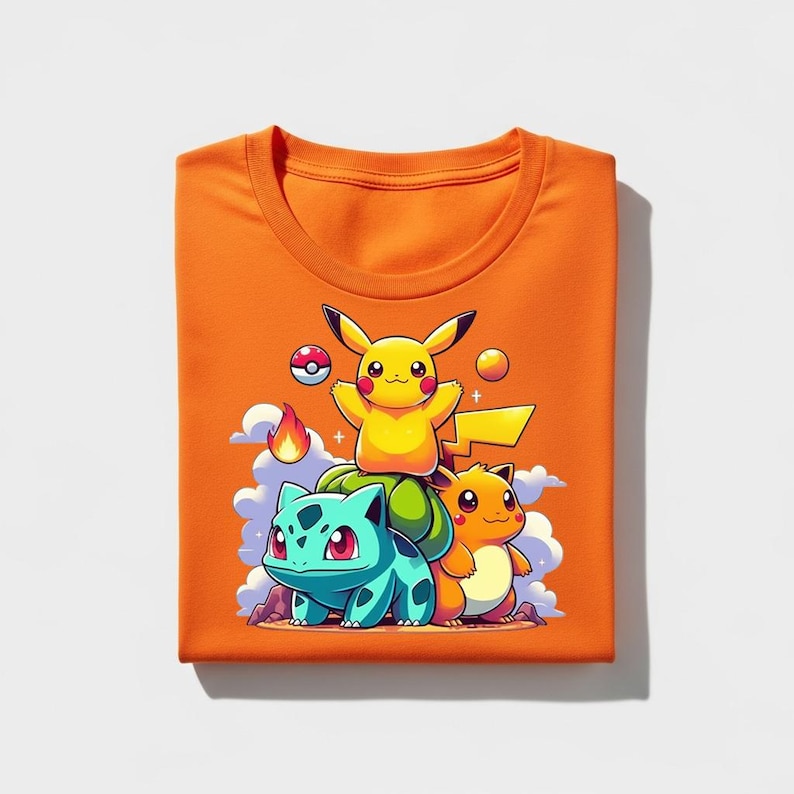 Peut inclure: T-shirt orange vif avec un dessin anim&eacute; de Pikachu, Bulbizarre et Salam&egrave;che de Pok&eacute;mon. Le motif comprend une Pok&eacute;ball, des flammes et des nuages. Le t-shirt est pli&eacute; proprement.