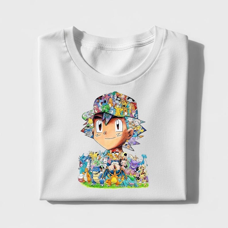 Peut inclure: T-shirt blanc avec un motif color&eacute; d'un personnage de dessin anim&eacute; portant un chapeau, entour&eacute; de cr&eacute;atures de dessins anim&eacute;s. Le motif est sur le devant du t-shirt pli&eacute;.