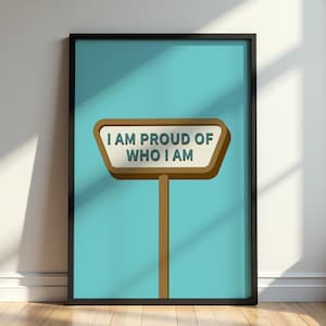 Könnte beinhalten: Gerahmter Kunstdruck mit türkisfarbenem Hintergrund, der ein braunes Wegweiserschild mit dem Text "I AM PROUD OF WHO I AM" in Weiß zeigt. Das Schild hat einen hellbraunen Rand und ist vor einem türkisfarbenen Hintergrund platziert.