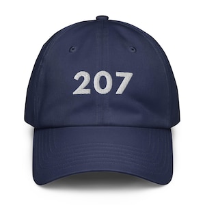 Peut inclure: Casquette de baseball bleu marine avec le numéro "207" brodé en blanc sur le devant. La casquette a une visière incurvée et une sangle réglable à l'arrière. Un accessoire décontracté classique.