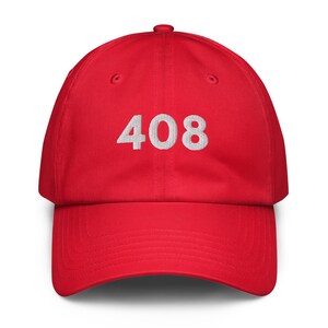 May include: A red baseball cap with the number "408" embroidered in white on the front. The cap has a curved brim and an adjustable strap at the back.