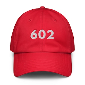 Peut inclure: Casquette de baseball rouge avec le numéro "602" brodé en blanc sur le devant. La casquette a une visière incurvée et une sangle réglable à l'arrière.