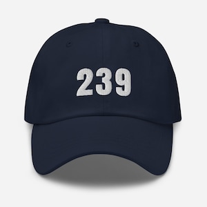 Puede incluir: Gorra de béisbol azul marino con el número "239" bordado en blanco en la parte delantera. La gorra tiene una visera curva y un diseño clásico de seis paneles. Un accesorio sencillo y elegante.