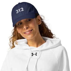 Puede incluir: Gorra de béisbol azul marino con el número "312" bordado en blanco. La gorra la lleva una persona que lleva una sudadera con capucha blanca.