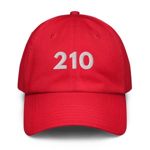 Peut inclure: Casquette de baseball rouge avec le numéro "210" brodé en blanc sur le devant. La casquette a une visière incurvée et une sangle réglable à l'arrière. Fabriquée dans un tissu doux et durable.