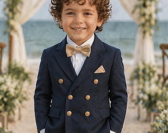 Traje de niño azul marino de doble botonadura con pantalón beige, ideal para bodas en la playa.