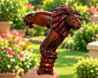 Puede incluir: Un mango de bastón de madera marrón oscuro pulido que presenta una cabeza de león tallada a mano con una melena detallada. El mango tiene una forma ergonómica suave que se extiende hacia una sección de cuello decorativa y texturizada.