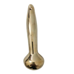 Puede incluir: Un tirador de puerta de lat&oacute;n macizo con un dise&ntilde;o suave y curvado. El tirador tiene una base bulbosa y una parte superior delgada y alargada con un peque&ntilde;o agujero. El acabado de lat&oacute;n le da un aspecto dorado.