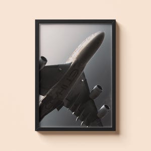 May include: A framed monochrome print of an aircraft in flight. The image shows the underside of the plane, with its wings and engines visible against a grey sky. The word "ETIHAD" is printed on the plane's body.