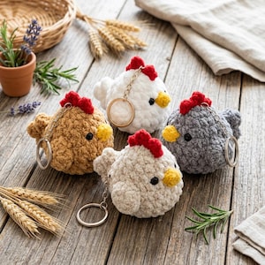 Könnte beinhalten: Vier gehäkelte Hühner-Schlüsselanhänger in den Farben Beige, Weiß, Hellgrau und Off-White. Jedes Huhn hat einen roten Kamm, einen gelben Schnabel und schwarze Augen. Sie sind an silbernen Schlüsselringen befestigt.