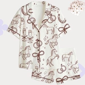 Op de afbeelding: Witte pyjamaset met een bruin paarden- en bruiloftthema. De set bevat een overhemd met korte mouwen en bijpassende shorts. Het ontwerp toont paarden, ringen, champagneglazen en strikken.