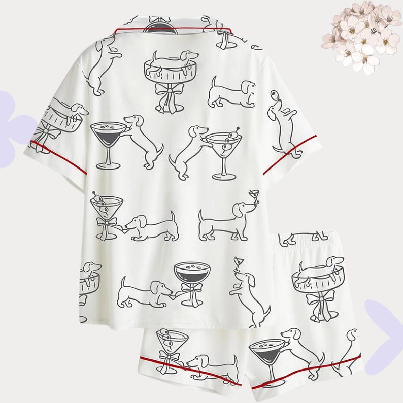 Puede incluir: Conjunto de pijama blanco con un patr&oacute;n de dibujo lineal negro repetido de perros salchicha y copas de martini. El conjunto incluye una camisa de manga corta con botones y pantalones cortos a juego, ambos ribeteados con ribete rojo.