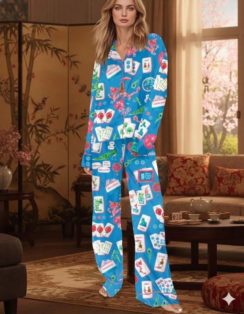 May include: A blue pajama set featuring a print of playing cards and other game-related graphics. The long-sleeved top and pants are made of a soft material. The pajama set is a comfortable sleepwear option.