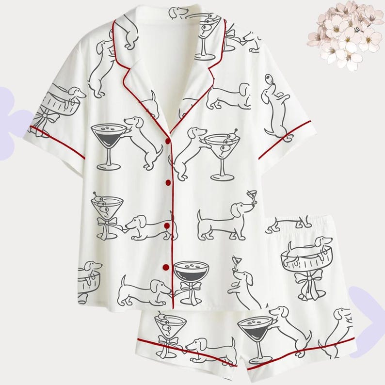Puede incluir: Conjunto de pijama blanco con un patr&oacute;n repetido de dibujo lineal negro de perros salchicha y copas de martini. El conjunto incluye una camisa de manga corta con botones y pantalones cortos, ambos con ribete rojo.