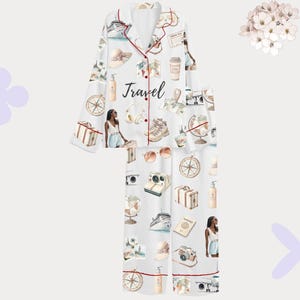 以下が含まれることがあります： 旅行をテーマにしたプリントの白いパジャマセット。長袖のボタンダウンシャツとマッチするパンツが含まれています。コンパス、パスポート、カメラ、クルーズ船など、旅行に関連するイラストがプリントされています。「Travel」の文字がシャツにプリントされています。