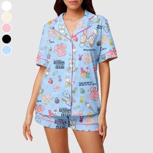May include: Light blue pajama set with a bunny and medical-themed print. The short-sleeved top and shorts feature pink trim and the text "Every Bunny's Favorite Nurse." The set includes images of bunnies, stethoscopes, and medical supplies.
