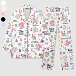 May include: White pajama set with a repeating pattern of Easter-themed graphics, including bunnies, bows, and medical supplies. The set features a collared button-down shirt and matching pants, trimmed with pink piping. Text includes "#NurseLife" and "Every Bunny's Favorite Nurse."