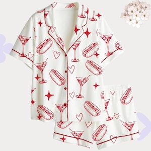 May include: White pajama set with a red trim, featuring a pattern of red hot dogs, martini glasses, hearts, and stars. The short-sleeved top has a button-down front, and the shorts have an elastic waistband. A fun and playful sleepwear set.