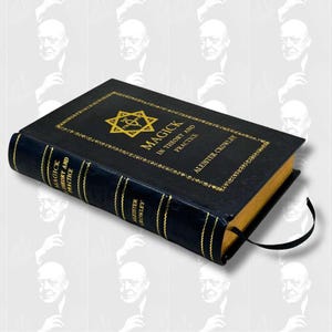 May include: A hardcover book titled "Magick in Theory and Practice" by Aleister Crowley. The book has a black cover with gold lettering and a gold star symbol. A black ribbon bookmark is attached.