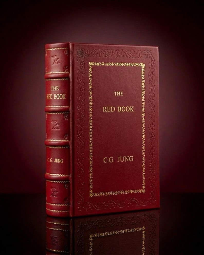 Op de afbeelding: Een rood hardcover boek getiteld "The Red Book" van C.G. Jung. Het boek heeft gouden letters en decoratieve gouden randen. De rug heeft gouden letters en reli&euml;fdesigns. Het boek staat rechtop.