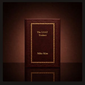 May include: A dark brown hardcover book titled The LSAT Trainer by Mike Kim. The front cover features a gold-colored rectangular border with intricate decorative patterns and gold lettering centered on the dark brown surface of the book.