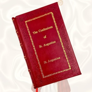 Könnte beinhalten: Ein rotes Hardcover-Buch mit dem Titel "Die Bekenntnisse des heiligen Augustinus". Das Buch hat goldene Schrift und dekorative goldene Ränder. Ein rotes Leseband ist sichtbar. Der Einband hat ein strukturiertes, geprägtes Design.