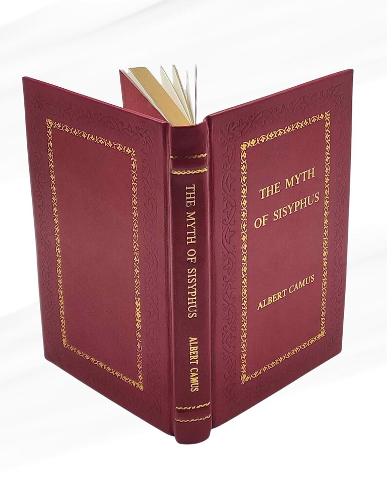 May include: A burgundy hardcover book, open to display its pages. The cover features gold decorative borders and the title "THE MYTH OF SISYPHUS" with the author, ALBERT CAMUS, in gold lettering. The page edges are also gold.
