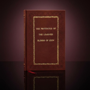 Può includere: Un libro con copertina rigida bordeaux e scritte dorate. Il titolo "THE PROTOCOLS OF THE LEARNED ELDERS OF ZION" è ben visibile. Il libro presenta un bordo dorato decorativo e un segnalibro a nastro rosso.