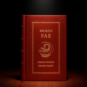 Op de afbeelding: Een rood hardcover boek met de titel "BROKEN FAE" in gouden letters. De omslag heeft een goudkleurig reliëf ontwerp en de namen van de auteurs, Caroline Peckham en Susanne Valenti. Donkere achtergrond.