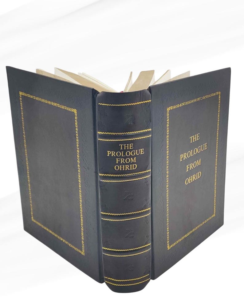 Puede incluir: Un libro de tapa dura con cubierta negra y detalles dorados. El lomo muestra "THE PROLOGUE FROM OHRID" en dorado. El libro est&aacute; abierto, mostrando las p&aacute;ginas.