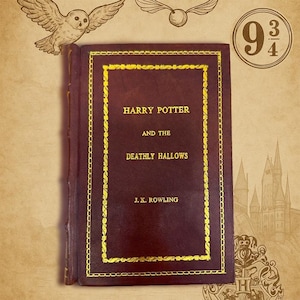 Può includere: Un libro con copertina rigida bordeaux con scritte dorate e bordo dorato, intitolato "Harry Potter e i Doni della Morte" di J.K. Rowling. L'immagine include illustrazioni di un gufo, un boccino d'oro e il numero 9 3/4.