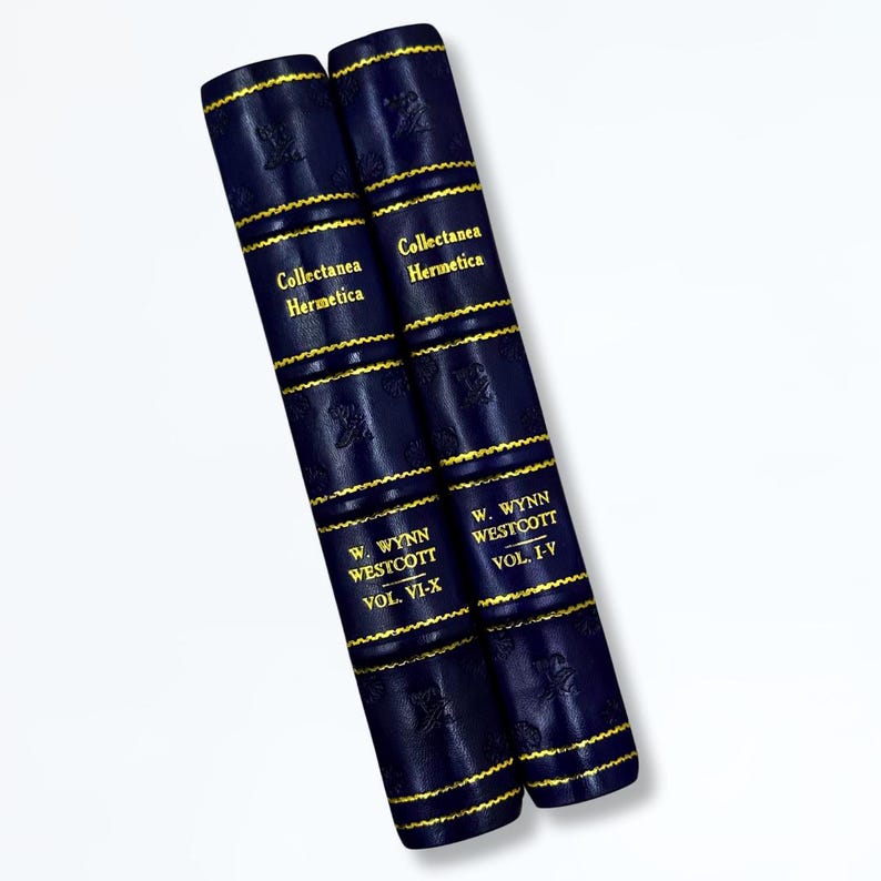 May include: Two navy blue leather-bound books with gold lettering and detailing. The spines display the titles "Collectanea Hermetica" and "W. Wynn Westcott, Vol. VI-X" and "Vol. I-V". The books have gold trim.