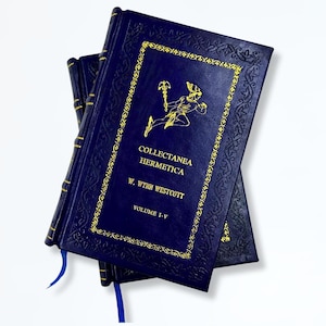 May include: A stack of dark blue hardcover books with gold lettering and decorative borders. The book title "Collectanea Hermetica" is visible, along with the author's name, W. Wynn Westcott, and "Volume I-V". Blue ribbon bookmarks are visible.