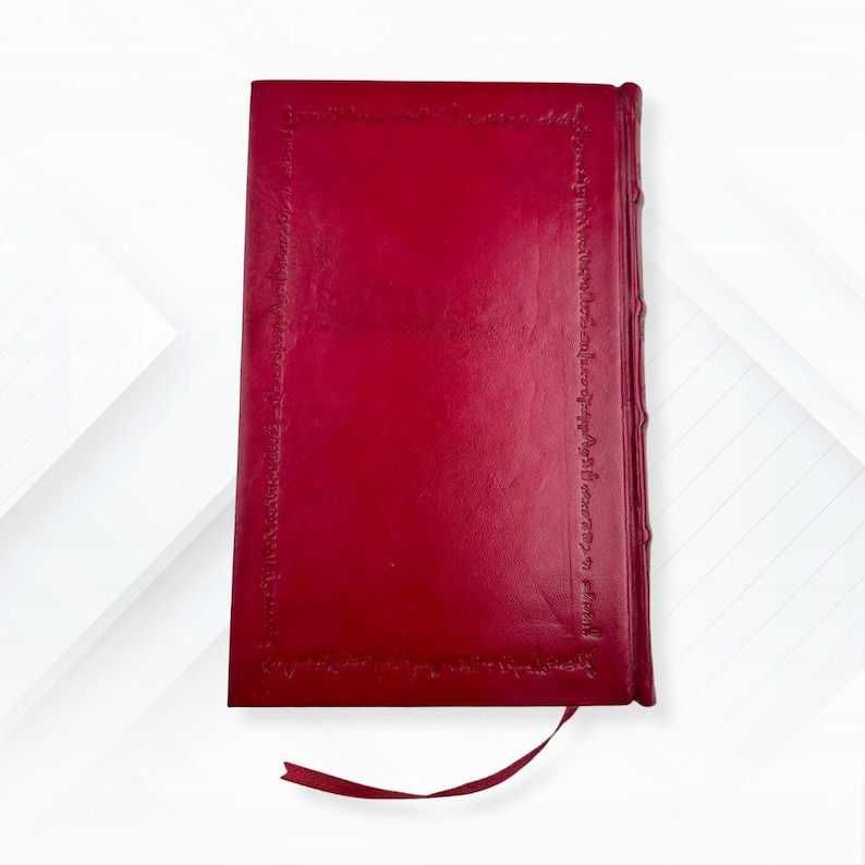Puede incluir: Un diario rojo encuadernado en cuero con un borde decorativo y un marcador de cinta a juego. La cubierta del diario es de color rojo intenso y los bordes de las p&aacute;ginas son visibles. El dise&ntilde;o general es cl&aacute;sico y elegante.