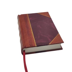 K&ouml;nnte beinhalten: Ein Hardcover-Journal mit burgunderfarbenem Einband und dekorativem Goldrand. Der Buchr&uuml;cken ist dunkler braun, und ein rotes Leseb&auml;ndchen ragt aus den Seiten. Die Seiten des Journals sind wei&szlig;.
