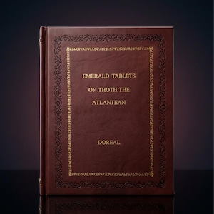 以下が含まれることがあります： 濃い赤色のハードカバーの本。タイトル「EMERALD TABLETS OF THOTH THE ATLANTEAN DOREAL」は金色の文字で印刷されています。表紙には、装飾的な金色のボーダーデザインが施されています。