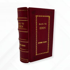 May include: A hardcover book titled "BACK TO EDEN" by Jethro Kloss. The book has a deep red cover with gold lettering and decorative gold accents. The spine also features gold lettering.