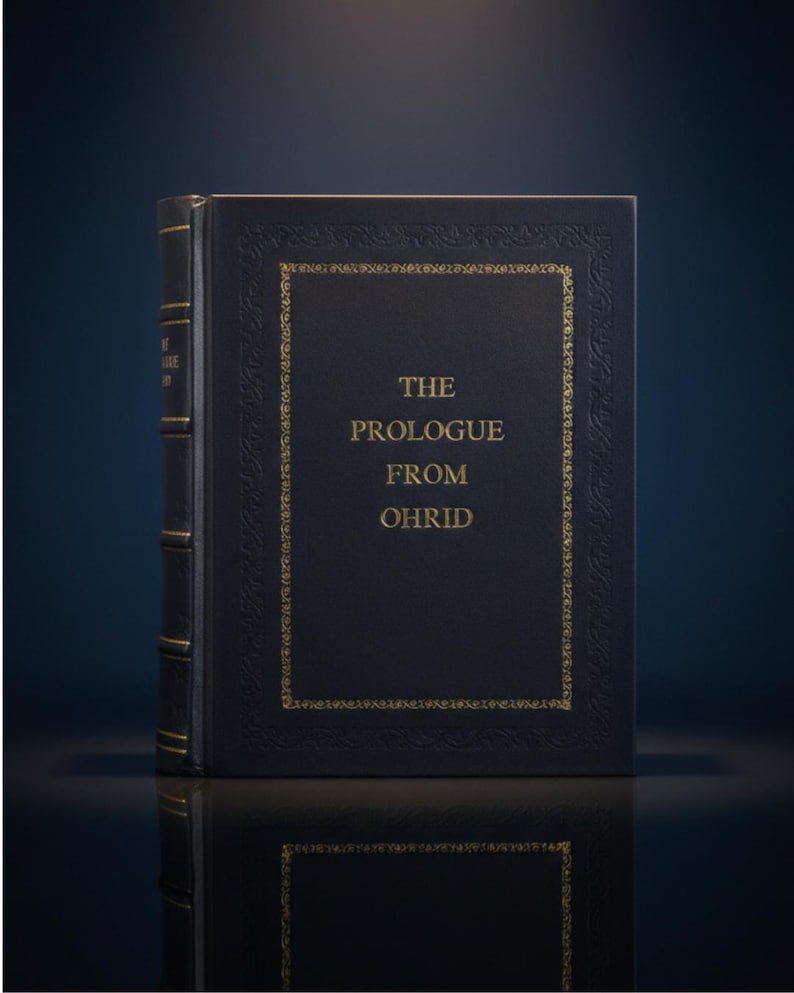 Puede incluir: Un libro de tapa dura azul oscuro con letras doradas y detalles decorativos. El t&iacute;tulo "THE PROLOGUE FROM OHRID" se muestra en la portada. El libro tiene detalles dorados y est&aacute; sobre una superficie reflectante.