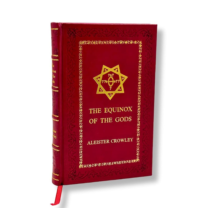 Op de afbeelding: Een rood hardcover boek getiteld "The Equinox of the Gods" van Aleister Crowley. Het boek heeft gouden letters en een decoratieve rand. Een gouden embleem staat in het midden van de voorkant, met een rood lint als boekenlegger.
