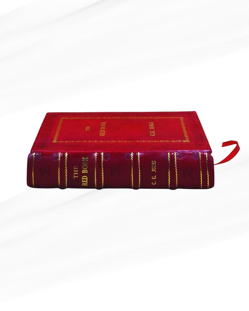 Op de afbeelding: Een rood hardcover boek getiteld "The Red Book" van C.G. Jung. Het boek heeft gouden letters en details. Een rood lint als boekenlegger is zichtbaar. Het boek staat tegen een witte achtergrond.