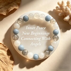 May include: A beaded bracelet with white, light blue, and clear beads. The bracelet is displayed on a white circular surface with the words "Inner Peace, New Beginnings, Connecting With Angels".