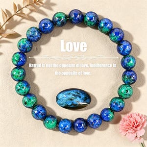 Könnte beinhalten: Ein Armband mit blauen und grünen Kugeln. Ein ovaler Stein mit blau-grünen Mustern liegt daneben. Das Wort "Love" steht über einem Zitat über Liebe und Gleichgültigkeit.