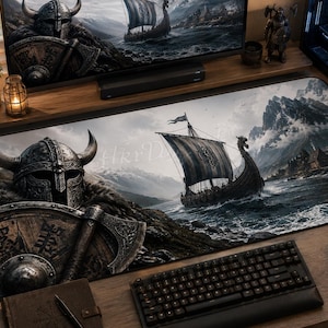 May include: A rectangular desk mat featuring a detailed illustration of a Viking warrior wearing a horned helmet and holding a round shield and axe, alongside a longship sailing on choppy water toward a mountainous, snow-covered coastline.