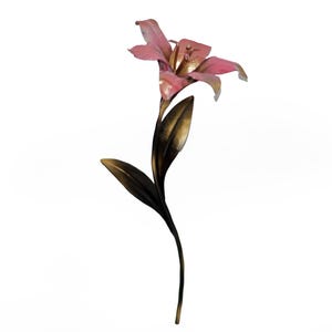 May include: A decorative metal lily flower sculpture featuring a single pink bloom with a golden center, attached to a long, slender, dark bronze-toned stem with two pointed leaves extending from the side, presented against a plain white background.