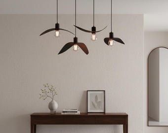 May include: A modern interior scene featuring a dark wood console table with decor, a patterned rug, and a large arched mirror. Above, four pendant lights with dark brown, wing-shaped shades hang from a black bar, illuminating the space.
