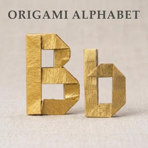 Könnte beinhalten: Goldene Origami-Buchstaben 'B' und 'b' auf neutralem Hintergrund. Der Großbuchstabe 'B' und der Kleinbuchstabe 'b' sind aus gefaltetem Papier mit einer strukturierten, metallisch goldenen Oberfläche gefertigt. Der Text 'ORIGAMI ALPHABET' steht darüber.