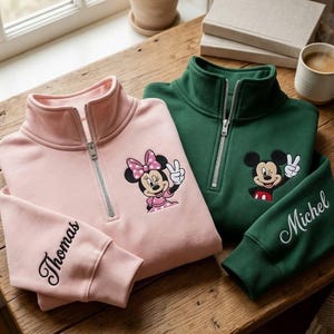 Pu&ograve; includere: Due felpe con zip a un quarto, una rosa e una verde, con personaggi dei cartoni animati ricamati. La felpa rosa presenta Minnie Mouse, e quella verde ha Topolino. Entrambe hanno nomi ricamati sulle maniche.
