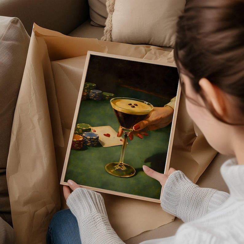May include: A framed rectangular print depicting a hand holding a martini glass filled with a dark liquid topped with foam and three coffee beans. The scene includes stacks of colorful poker chips and a playing card on a green felt table surface.